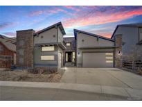 Striking modern exterior with stone accents, two-car garage and inviting curb appeal at sunset at 9750 Taylor River Cir, Littleton, CO 80125