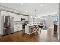 Modern kitchen boasts white cabinets, stainless steel appliances, and a center island, blending style with functionality at 1919 Eaton St, Lakewood, CO 80214