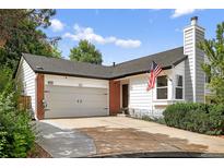 Charming home featuring a two-car garage, red brick, concrete driveway, an American flag, and mature landscaping at 1102 Conifer Ct, Highlands Ranch, CO 80126