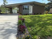 Charming brick home with a carport and a beautifully landscaped front yard featuring vibrant flowers and a well-maintained lawn at 3355 Moorhead Ave, Boulder, CO 80305