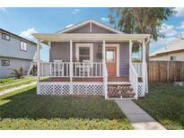 Charming gray home featuring a cozy front porch with white railings and an inviting orange door at 130 N 8Th Ave, Brighton, CO 80601