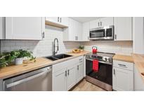 Modern kitchen featuring stainless steel appliances, white cabinets, and butcher block countertops at 9700 E Iliff Ave # A3, Denver, CO 80231