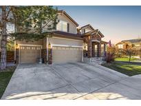 Inviting home featuring a three-car garage, stone accents, and manicured lawn at sunset at 15310 E 108Th Way, Commerce City, CO 80022