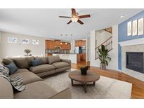 Open-concept living room adjacent to the kitchen features a fireplace, wood floors, and a ceiling fan at 22898 E Saratoga Pl, Aurora, CO 80015