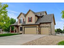 Charming two-story home featuring a three-car garage, stone accents, and well-manicured landscaping at 1864 Malibu Ct, Fort Lupton, CO 80621