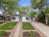 Charming single-story home with a well-manicured front yard, lush lawn, and mature trees at 2967 Olive St, Denver, CO 80207