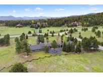 Expansive estate on a verdant lot featuring mature trees, long driveway, and mountain views at 32399 Woodland Dr, Evergreen, CO 80439