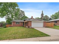 Charming brick home with a well-manicured lawn, mature trees, and attached two-car garage at 6011 Welch St, Arvada, CO 80004