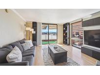 Bright living room with a comfortable gray sofa and a sliding glass door leading to a balcony with mountain views at 1301 Speer Blvd # 403, Denver, CO 80204