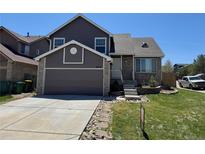 Charming home with a two-car garage, stone accents, manicured lawn, and inviting walkway at 6610 Monaco Way, Brighton, CO 80602