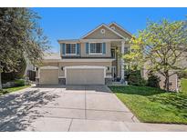Inviting two-story home with a well-maintained lawn, a three-car garage, and charming curb appeal on a sunny day at 6039 S Ukraine Cir, Aurora, CO 80015