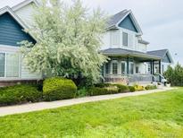 Inviting two-story home with a charming covered porch and beautifully landscaped front yard at 935 Green Gables Cir, Bennett, CO 80102