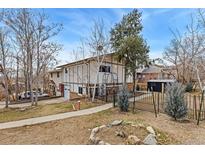 Two story home with fenced yard, driveway, and mature trees on a sunny day at 159 Judson St, Longmont, CO 80501