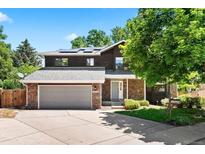 Charming two-story home with a stone and dark wood exterior, a well-maintained lawn, and a two car garage at 4906 S Crystal St, Aurora, CO 80015