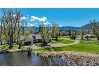 Beautiful home featuring an attached garage, pond, luscious green grass, and mountain views on a bright sunny day at 16440 Old Denver Rd, Monument, CO 80132