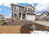 Charming two-story home featuring stone accents, a two-car garage and professionally landscaped yard with rock and mulch at 3074 Belleville Ridge Rd, Elizabeth, CO 80107