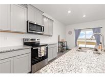 Modern kitchen with gray cabinets, granite countertops, and stainless steel appliances and eat-in bar at 3074 Belleville Ridge Rd, Elizabeth, CO 80107