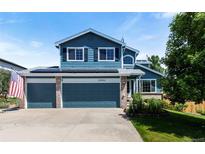 Charming two-story home with a three-car garage, blue siding, manicured lawn, solar panels, and American flag at 21885 Whirlaway Ave, Parker, CO 80138