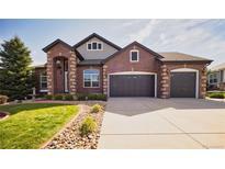 Charming two-story brick home with a well-manicured lawn and a three-car garage, perfect for a growing Gathering at 7472 Iridium Way, Castle Rock, CO 80108
