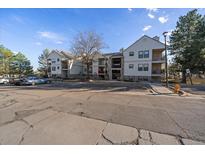 Multi-level condominium building with balconies, parking, and mature trees on a sunny day at 6705 S Field St # 801, Littleton, CO 80128