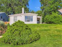 Charming home with a lush green lawn, mature trees, and freshly painted exterior at 2626 N Steele St, Denver, CO 80205