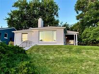 Charming home featuring a brick facade, lush lawn, and mature trees under a clear, blue sky at 2626 N Steele St, Denver, CO 80205