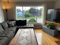 Cozy living room featuring a large window with neighborhood views, a sectional sofa, and a rustic wood coffee table at 2626 N Steele St, Denver, CO 80205