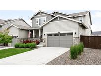 Charming two-story home with gray siding, stone accents, landscaped yard, and a welcoming covered porch at 14454 Grape Way, Brighton, CO 80602