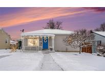 Charming single-story home featuring a covered porch, blue door with wreath, and snow-covered yard at 11 S Perry St, Denver, CO 80219