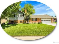 Charming two-story home featuring a well-manicured lawn, brick accents, and mature trees, set under a beautiful blue sky at 6810 S Marion W Cir, Centennial, CO 80122