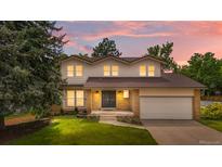 Charming two-story home with well-maintained lawn and warm exterior lighting at dusk at 10724 E Maplewood Pl, Englewood, CO 80111