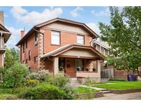 Charming brick two-story home with a covered front porch and mature landscaping at 1430 Monroe St, Denver, CO 80206