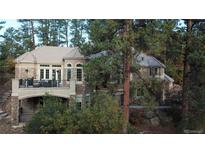 Beautiful home with a stone facade, a balcony and a lush green landscape with mature trees at 226 Hidden Valley Ln, Castle Rock, CO 80108