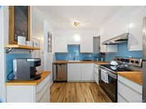 Bright kitchen features modern appliances, white cabinetry, butcher block countertops, and blue tile backsplash at 9240 W 49Th Ave # 317, Wheat Ridge, CO 80033