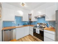 Bright kitchen features white cabinets, wood countertops, stainless steel appliances, and blue backsplash at 9240 W 49Th Ave # 317, Wheat Ridge, CO 80033