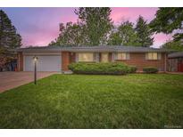 Charming single-story brick home with a well-manicured lawn and attached garage at dusk at 13558 E Center Ave, Aurora, CO 80012