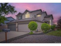 Charming home with a two-car garage, gray brick accents, and well-maintained landscaping at dusk at 401 W 114Th Pl, Northglenn, CO 80234