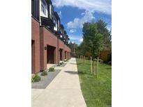 Modern townhome with brick facade, individual garages, and landscaped walkway and yard at 2142 Applewood Dr, Lakewood, CO 80215