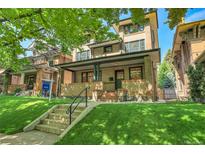 Charming brick home with a covered front porch and lush green lawn at 1343 Milwaukee St, Denver, CO 80206