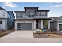 Attractive two-story home with a stone-accented facade, gray siding, and a spacious two car garage at 8585 Eckley St, Littleton, CO 80125