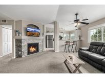 Cozy living room features a stone fireplace and a view into the modern kitchen with breakfast bar at 6840 Xavier Cir # 5, Westminster, CO 80030