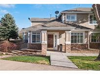 Charming townhouse entrance featuring stone accents, well-maintained landscaping, and a welcoming front door at 7524 Pineridge Trl, Castle Pines, CO 80108