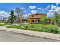 Charming two-story home with a fenced front yard, mature trees, and blue sky at 6671 Grove St, Denver, CO 80221
