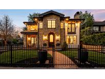 Stunning stone home with manicured lawn, fence, and illuminated arched entryway at 2400 S Columbine St, Denver, CO 80210