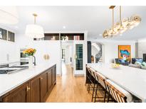 Bright, open kitchen boasts a large island, modern lighting, wine cooler, and seamless flow to adjacent living spaces at 2400 S Columbine St, Denver, CO 80210