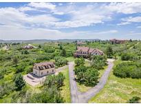Expansive aerial view of an estate, showcasing lush landscaping, a guest house, and stunning mountain views at 1091 Colt Cir, Castle Rock, CO 80109