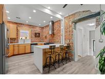 Stylish kitchen with brick accent wall, modern island, stainless steel appliances, and updated fixtures at 3354 Vallejo St, Denver, CO 80211