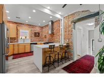 Bright kitchen boasts a brick accent wall, stainless steel appliances, and a modern island with seating at 3354 Vallejo St, Denver, CO 80211