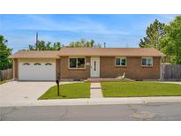Charming single-story brick home with a manicured lawn, attached garage, and inviting front entrance at 6180 W 77Th Pl, Arvada, CO 80003