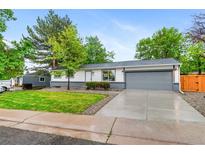 Charming ranch-style house featuring a manicured front lawn, mature trees, and a two-car garage at 4672 S Lewiston Way, Aurora, CO 80015